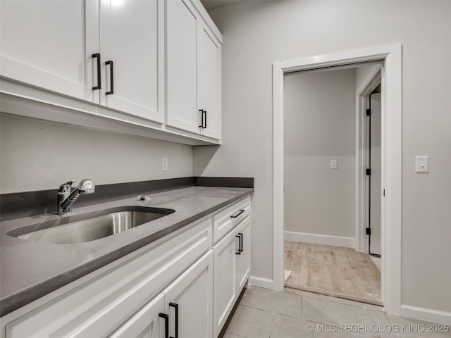 kitchen with light tile patterned floors, sink, and white cabinetry