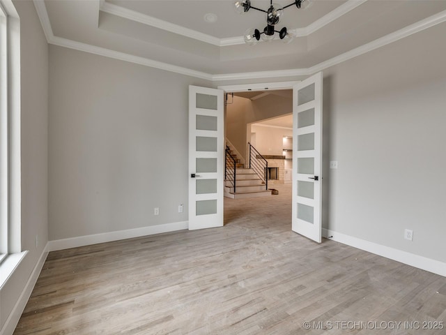 empty room with a chandelier, crown molding, french doors, and a tray ceiling