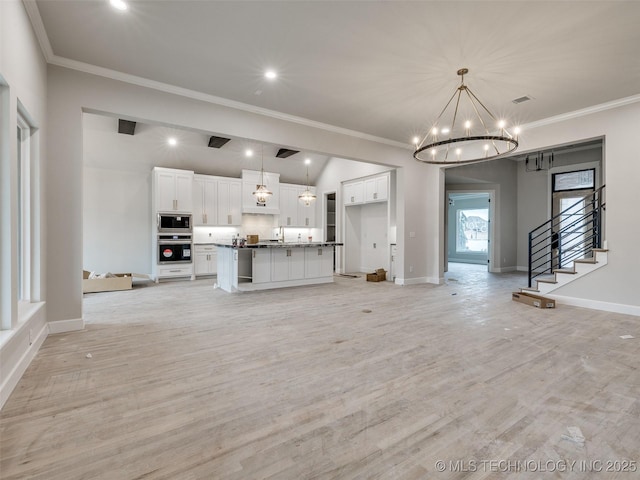 unfurnished living room with light hardwood / wood-style flooring, ornamental molding, and a chandelier