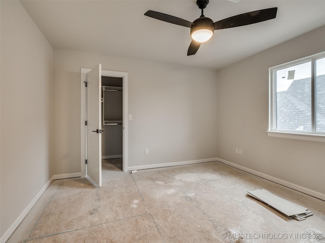 unfurnished bedroom with ceiling fan, a spacious closet, and a closet