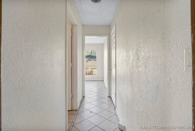 hall with light tile patterned floors and a textured ceiling