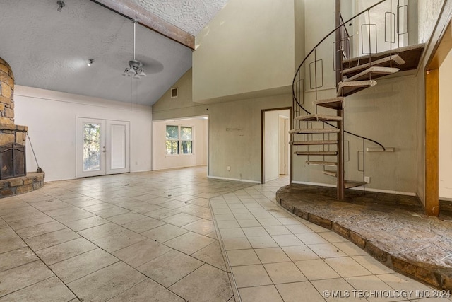 unfurnished living room featuring a textured ceiling, ceiling fan, high vaulted ceiling, beamed ceiling, and a fireplace