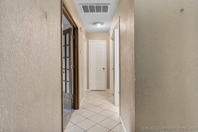 corridor with light tile patterned flooring and a textured ceiling