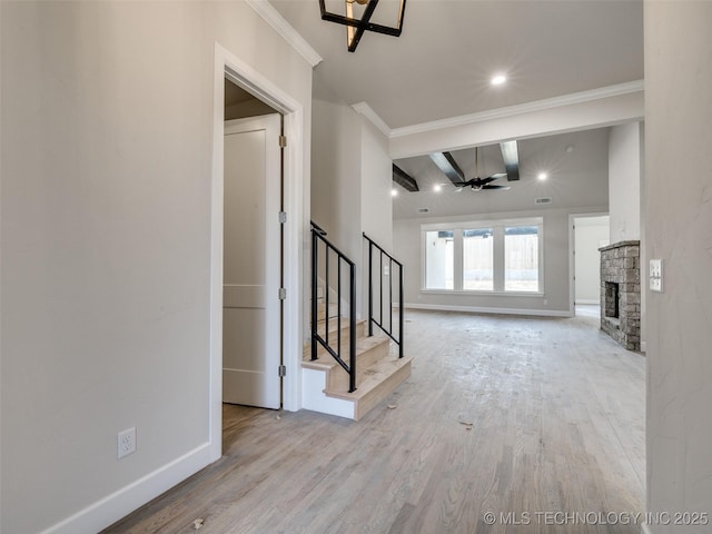 entryway with light hardwood / wood-style flooring, ceiling fan, beam ceiling, a fireplace, and ornamental molding