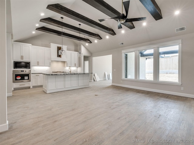 kitchen featuring white cabinetry, black microwave, a center island, decorative light fixtures, and oven