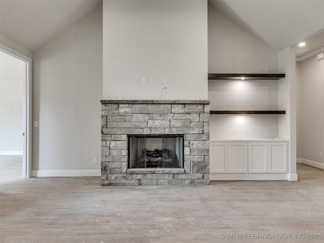 unfurnished living room featuring vaulted ceiling, a fireplace, and light hardwood / wood-style floors