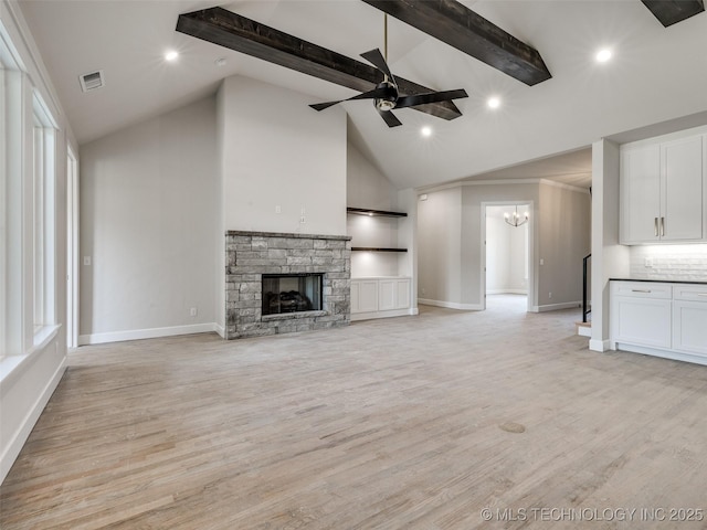 unfurnished living room featuring ceiling fan with notable chandelier, high vaulted ceiling, a fireplace, beamed ceiling, and light hardwood / wood-style floors