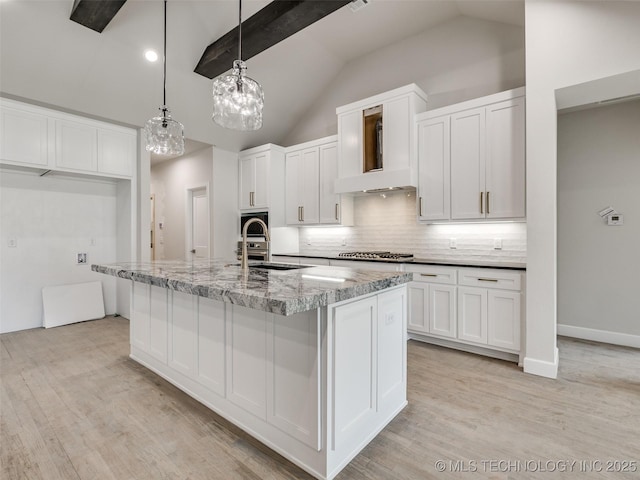 kitchen featuring white cabinetry, sink, decorative light fixtures, and a center island with sink