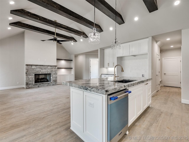 kitchen featuring white cabinetry, sink, stainless steel dishwasher, and stone countertops