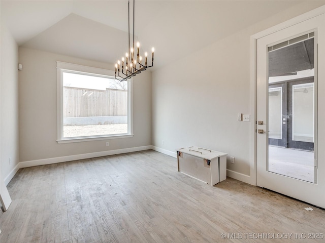 spare room featuring lofted ceiling, light hardwood / wood-style floors, and a notable chandelier