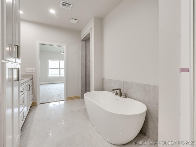 bathroom with a washtub, vanity, and tile patterned flooring