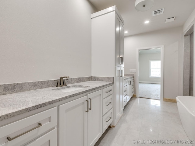 bathroom featuring vanity, a washtub, and tile patterned floors