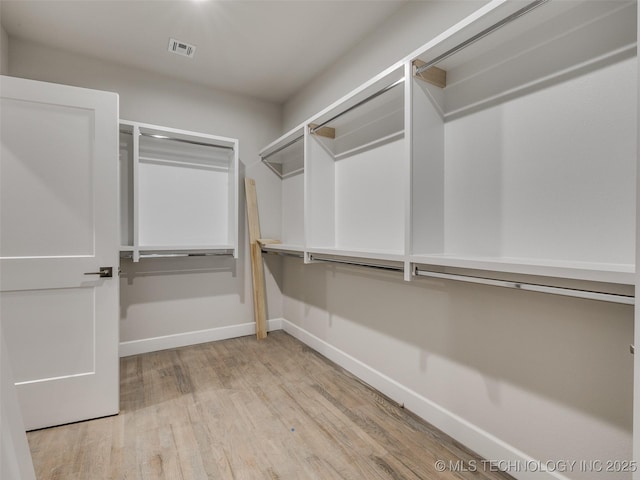 walk in closet with light hardwood / wood-style floors