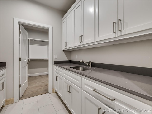 laundry area featuring light tile patterned flooring and sink