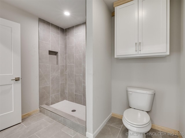 bathroom with tile patterned floors, toilet, and a tile shower