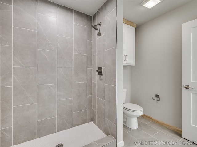 bathroom featuring tiled shower, tile patterned floors, and toilet