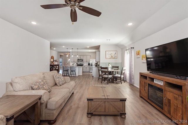 living room featuring ceiling fan, lofted ceiling, and light wood-type flooring