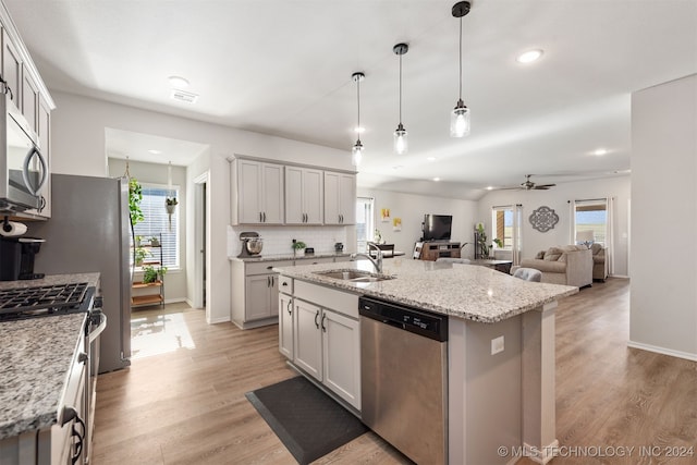 kitchen with a kitchen island with sink, sink, a healthy amount of sunlight, and appliances with stainless steel finishes