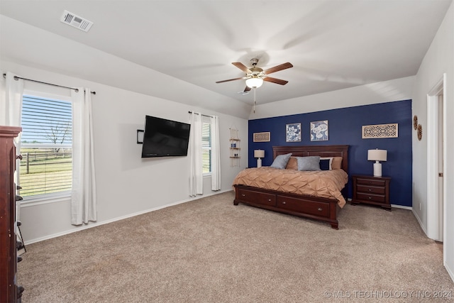 bedroom with ceiling fan, light colored carpet, and multiple windows