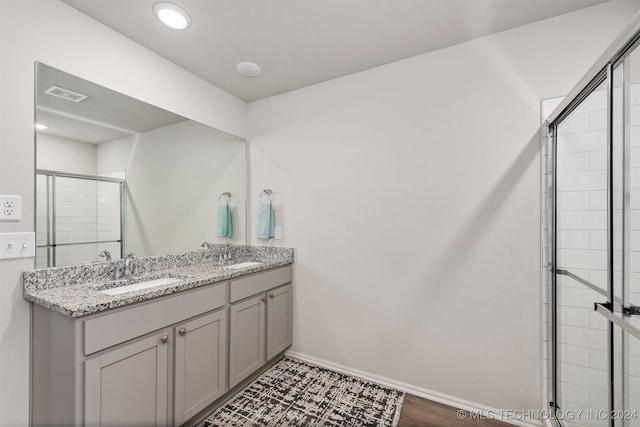 bathroom with hardwood / wood-style floors, vanity, and a shower with door