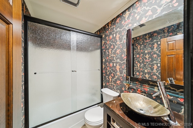 full bathroom with vanity, toilet, bath / shower combo with glass door, and crown molding