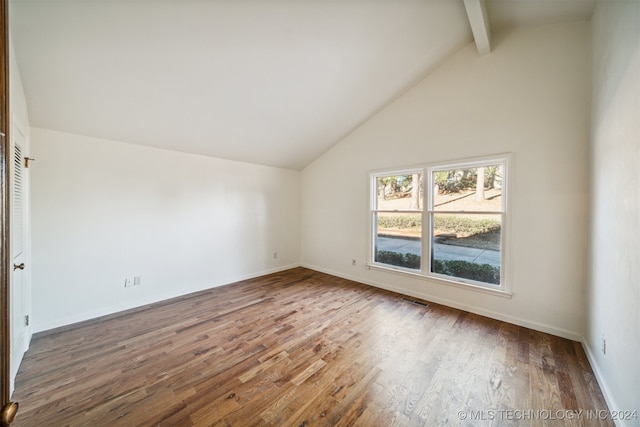 unfurnished room featuring beam ceiling, hardwood / wood-style floors, and high vaulted ceiling