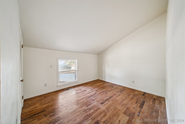 unfurnished room with dark hardwood / wood-style flooring and lofted ceiling