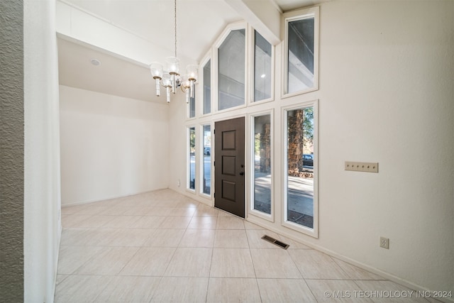 tiled entrance foyer with an inviting chandelier and high vaulted ceiling