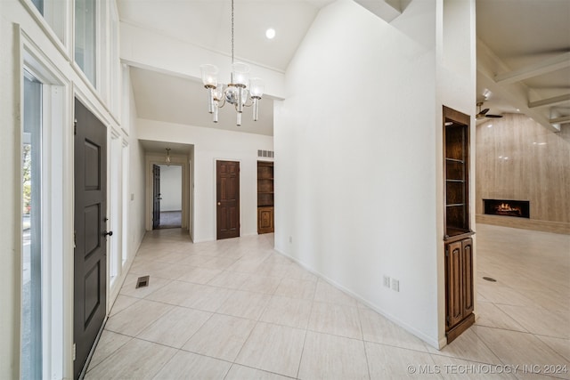 corridor featuring light tile patterned floors, a chandelier, and high vaulted ceiling