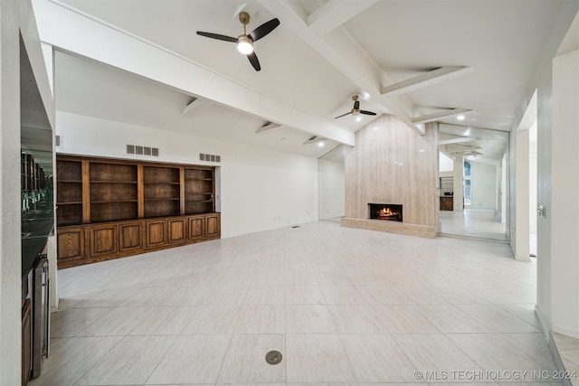 unfurnished living room with ceiling fan, a large fireplace, and beamed ceiling