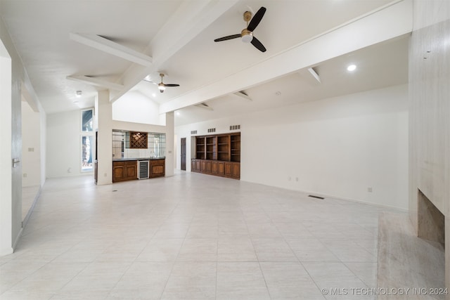 unfurnished living room featuring lofted ceiling with beams, ceiling fan, light tile patterned floors, a premium fireplace, and beverage cooler