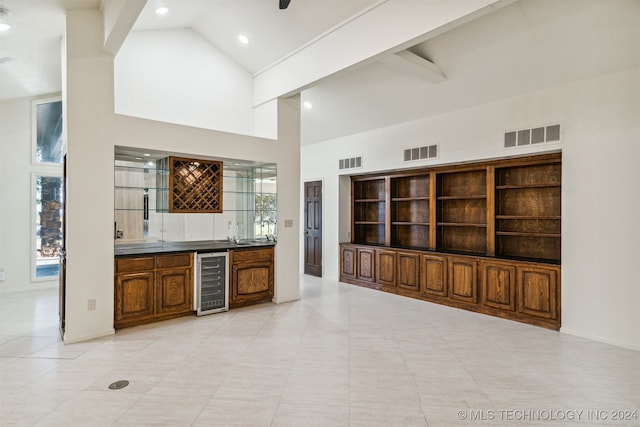 interior space with light tile patterned floors, high vaulted ceiling, beverage cooler, and sink