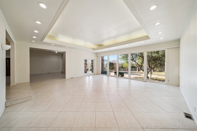 spare room with a tray ceiling, crown molding, and light tile patterned flooring