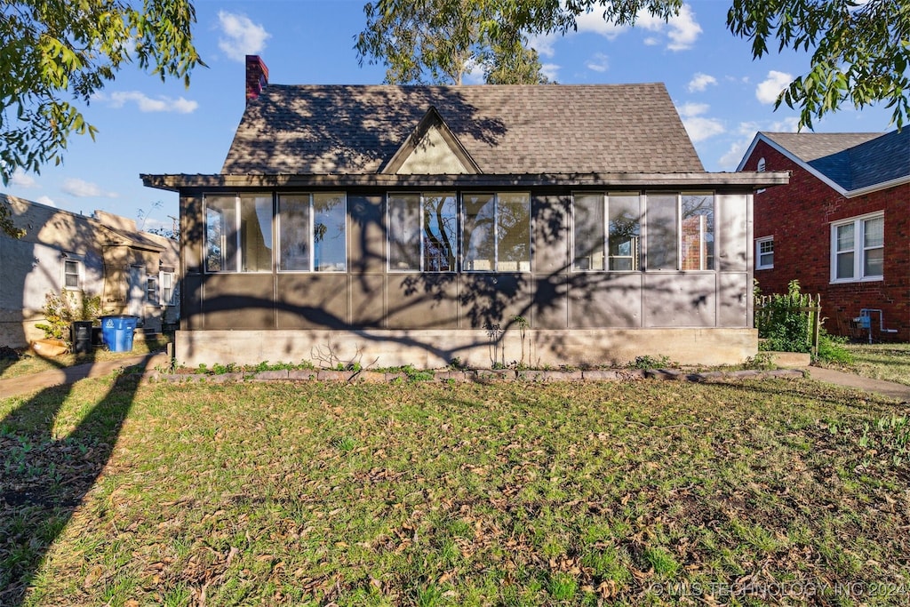 back of property featuring a sunroom and a yard