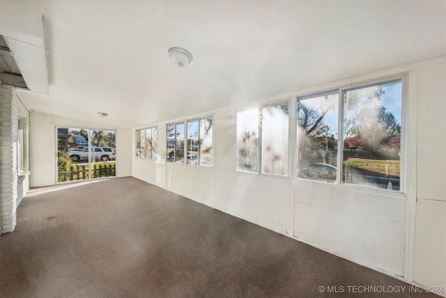 carpeted spare room featuring a healthy amount of sunlight and vaulted ceiling