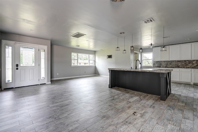 kitchen featuring a center island with sink, white cabinets, and a wealth of natural light