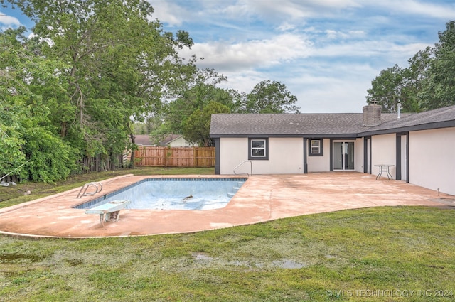 view of pool with a diving board, a yard, and a patio