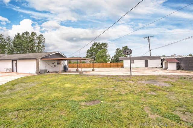 view of yard featuring a carport, an outdoor structure, and central AC