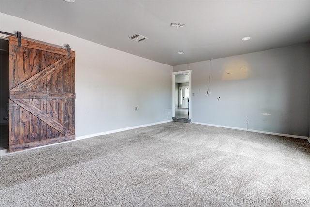 carpeted empty room featuring a barn door