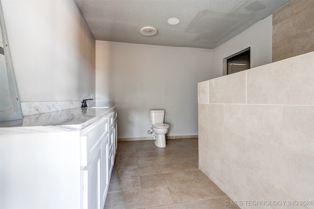 bathroom featuring tile patterned flooring, a textured ceiling, toilet, and sink