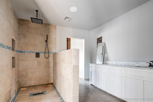 bathroom featuring tile patterned floors, vanity, a textured ceiling, and tiled shower