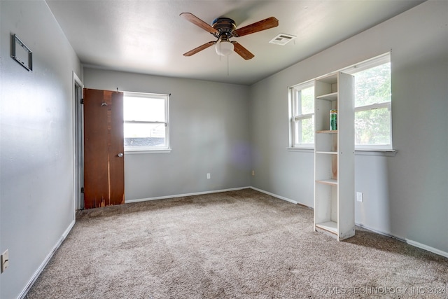 empty room featuring plenty of natural light, ceiling fan, and light carpet