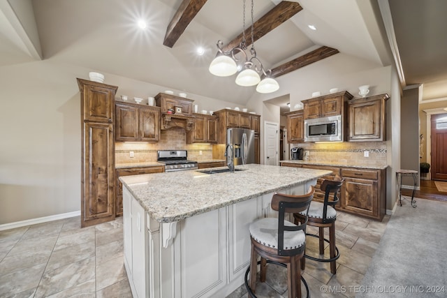 kitchen featuring decorative backsplash, appliances with stainless steel finishes, a kitchen island with sink, and sink