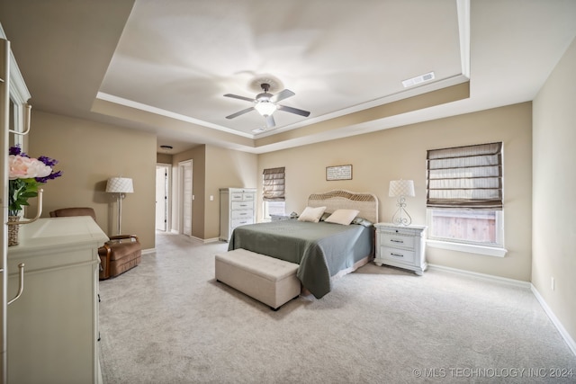 bedroom with a raised ceiling, ceiling fan, and light carpet