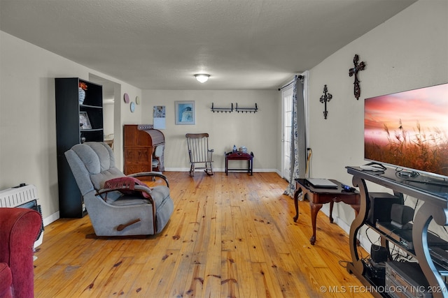 living room featuring a textured ceiling, heating unit, and light hardwood / wood-style flooring