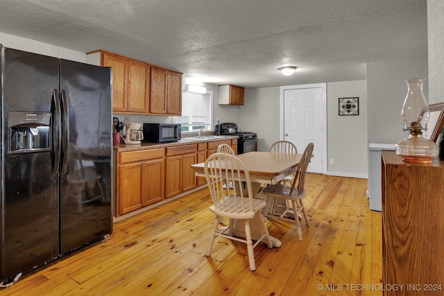 kitchen featuring black appliances, a textured ceiling, and light hardwood / wood-style flooring