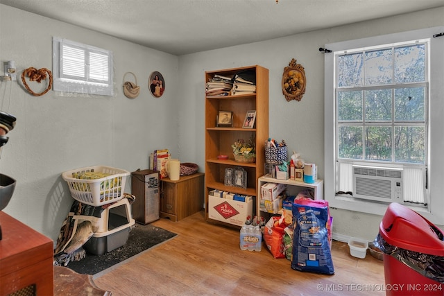 recreation room with cooling unit, light wood-type flooring, and a textured ceiling