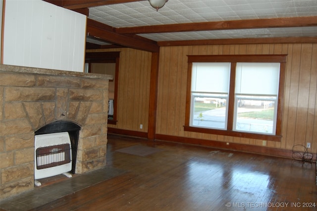 unfurnished living room with heating unit, wooden walls, beamed ceiling, dark hardwood / wood-style floors, and a stone fireplace