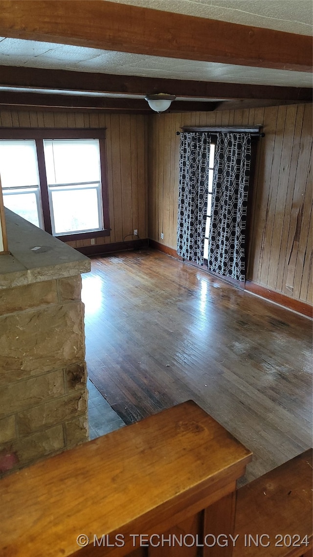 spare room featuring hardwood / wood-style floors, wood walls, and beamed ceiling