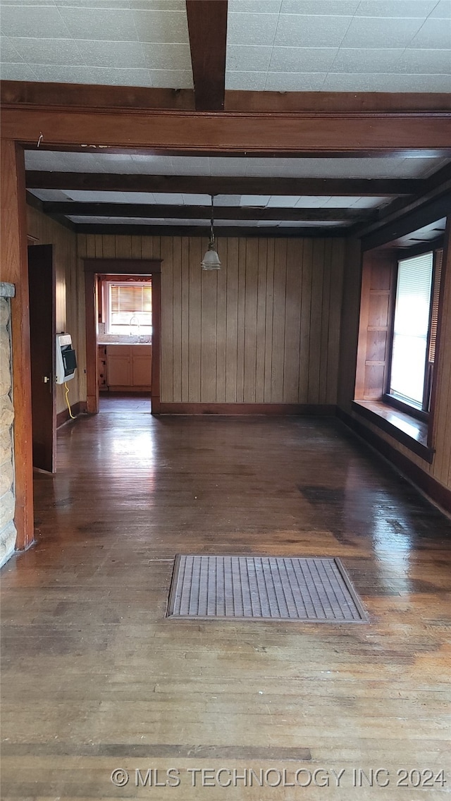 interior space featuring beam ceiling, dark wood-type flooring, and wooden walls